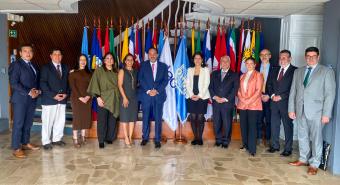 Funcionarios de las entidades posan en frente de sus banderas durante la firma del acuerdo.